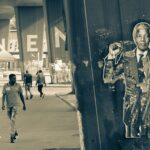 An image of a man walking past nelson mandela's statues