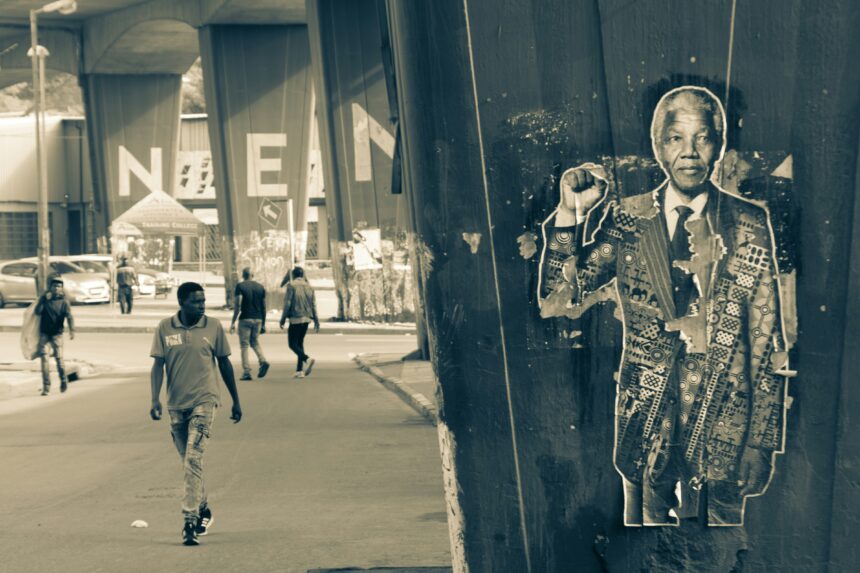 An image of a man walking past nelson mandela's statues